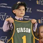 JP Gibson held his jersey as Utah Jazz president Randy Rigby (right) and his father Josh Gibson and sister Elie looked on.