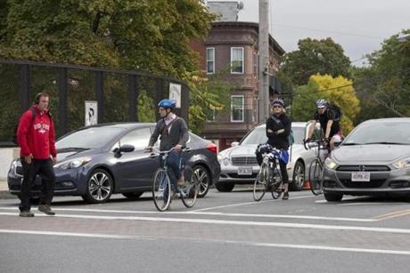 Bicyclists at the corner of Somerville Avenue and Beacon Street wait for the green light.
