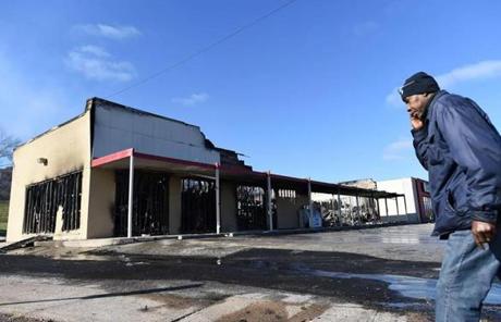 A man walked past a burnt-out store in Ferguson, Mo., that was set ablaze following the grand jury decision Monday night.
