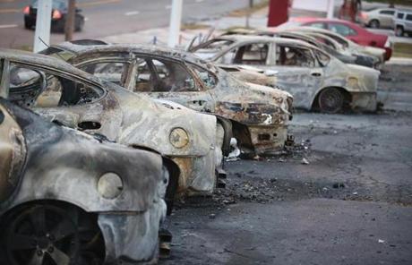 Cars that were set on fire when rioting erupted sat on a lot in Dellword, Mo.
