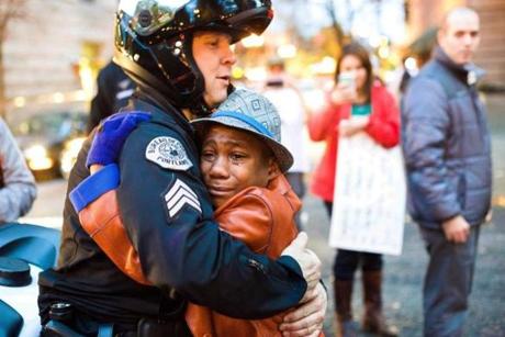 In this Tuesday, Nov. 25, 2014 photo provided by Johnny Nguyen, Portland police Sgt. Bret Barnum, left, and Devonte Hart, 12, hug at a rally in Portland, Ore., where people had gathered in support of the protests in Ferguson, Mo. (AP Photo/Johnny Huu Nguyen)
