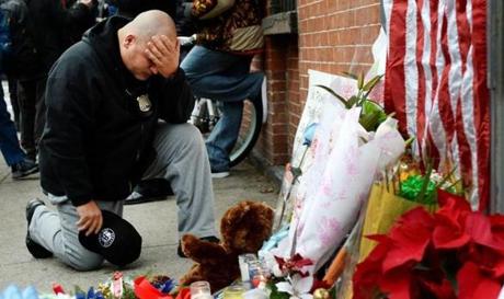A New York City police officers said a prayer while kneeling in front of small memorial for two police officers who were killed Saturday in New York.
