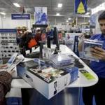 FILE - In this Nov. 27, 2014 file photo, Best Buy employee Daruosh Habbir helps holiday shoppers check out goods at Best Buy in Northbrook, Ill. The Commerce Department reports on consumer spending and income in November on Tuesday, Dec. 23, 2014. (AP Photo/Nam Y. Huh, File)