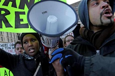 Sheillanme Wambui, a senior at the University of Massachusetts, shouted slogans as Brock Satter held the megaphone for her during the protest.
