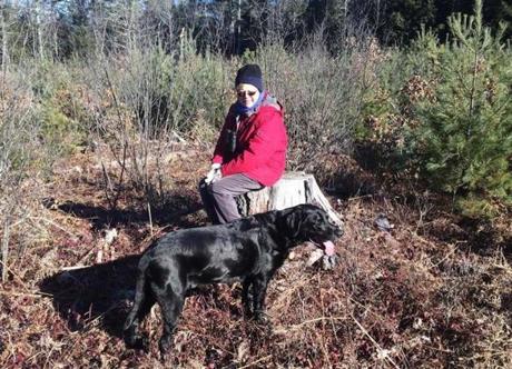 Roseanne Carruthers of Stoneham sat in a clearing in Barre on New Year?s Day, which would have been her son Neil?s 36th birthday. With her is Bear, Neil?s dog. 
