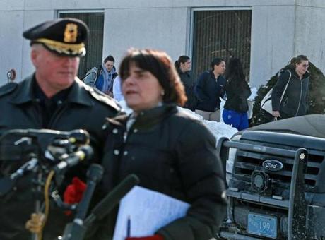 02/17/15: Tewksbury, MA: A man was shot dead by Tewksbury police today following an incident in the parking lot of the Salter School. As Middlesex County D.A. Marian Ryan (foreground center) and Tewksbury Police Chief Timothy Sheehan (foreground left) speak to reporters at the entrance to the school's parking lot, students are pictured leaving the building for the day. (Globe Staff Photo/Jim Davis) section:Metro topic: Tewksbury Shooting
