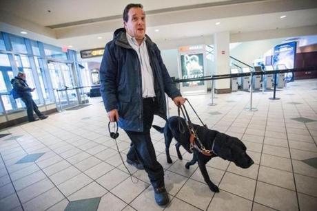 Carl Richardson and his service dog enter AMC Loews Boston Common Theater to see ?American Sniper.? Richardson receives a special hearing device to enjoy the film.

