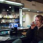Elise Anderson, 29, of Chelsea, consumes a drink after work recently at Scholars American Bistro & Cocktail Lounge in Boston. Anderson said that she once worked at a company where staff members ? who worked long hours ? often drank wine on Friday afternoons.