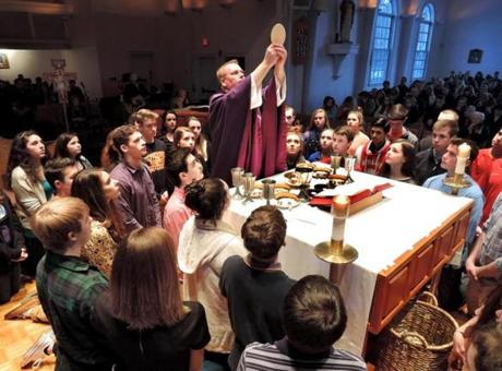 At the Life Teen Mass at St. Mary of the Sacred Heart Church in Hanover, youths gathered around the Rev. Chris Hickeyon the altar for the consecration of the eucharist. 

