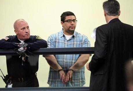 Carlos Colina (center) spoke with his attorney, John Cunha, Jr., during his arraignment in Cambridge District Court on Monday.
