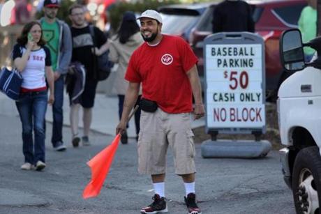 Parking attendant Earl Grant directed cars to a lot off Van Ness Street near Fenway Park on Monday.
