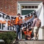 Tyler Van Valkenburg (left) and Maryssa Baron (center), of Divest Harvard, spoke to a fellow student while blocking the entrance to a Harvard administration building.