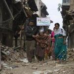 Nepalese people in search of shelter walked along a narrow road past a destroyed building Sunday.