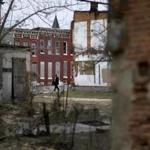 A man walked past boarded-up houses and vacant lots in Baltimore. One-third of Baltimore households live on less than $25,000 each year.