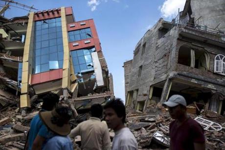 People walked past a collapsed building after a fresh 7.3 earthquake struck in Kathmandu, Nepal. 
