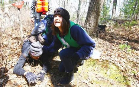 Claire Boine, a participant in the simulations program organized by the Humanitarian Academy at Harvard University, works with others during a land mine drill at Harold Parker State Forest in Andover. 

