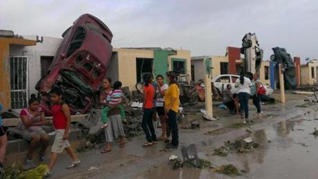 Residents stood outside their homes as damaged cars were seen after a tornado hit the town of Ciudad Acuna. 
