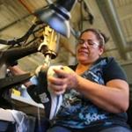 Eddy Maria Taveras used a hand-crank Singer sewing machine to make a repair on a running shoe at the New Balance factory in Lawrence.