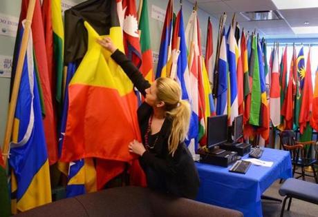 Student Joanna Konomi adjusted flags in Quincy College?s International Student Services office.
