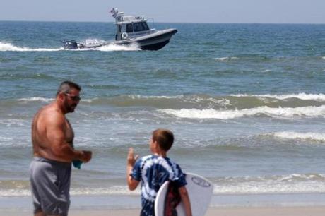Jack Cross, 9, watched as a boat patrolled the coastline near Ocean Crest Pier in Oak Island, N.C., on Monday. 

