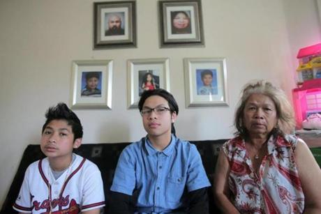 From left to right: Brian Sak, 12, Danny Sak, 15, and their paternal grandmother, Heng Phoeuk, sat together beneath portraits of the boys' parents and siblings. 
