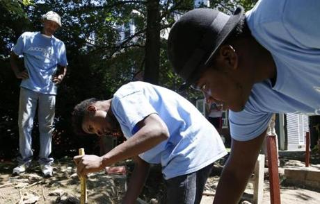 Kevin Corbin, city of Boston supervisor of the Industrial School for Girls site, watched as Khaivon Castro, 21, of the South End measured the depth of a hole dug to excavate part of a foundation while Jalen Campbell, 19, of Mattapan helped hold a line level. 
