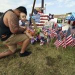 Bryan Thaboua knelt with his 8-month-old son in front of the Lee Highway memorial for last Thursday's Chattanooga, Tenn., shooting victims.