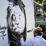 Artist Mark Balma paints a mural of Cecil, a well-known lion killed by dentist Walter Palmer during a guided bow hunting trip in Zimbabwe, as part of a silent protest outside Palmer?s office in Bloomington, Minn., on Wednesday.