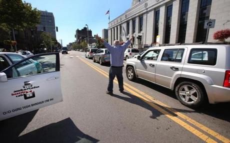 Cab driver Michael Gervais stopped his taxi and stood in the middle of Massachusetts Avenue Monday to protest ride-hailing services such as Uber and Lyft. 
