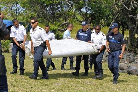 French police officers carried a piece of debris from a plane in Saint-Andre, Reunion Island.
