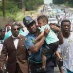 Missouri Highway Patrol Captain Ron Johnson carried a child in a march marking a year since Michael Brown?s death. 