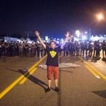 A demonstrator marking the anniversary of the shooting of Michael Brown stood in front of police at a protest Monday.