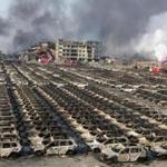 Smoke billowed from the site of an explosion that reduced a parking lot filled with new cars to charred remains at a warehouse in northeastern China's Tianjin municipality.