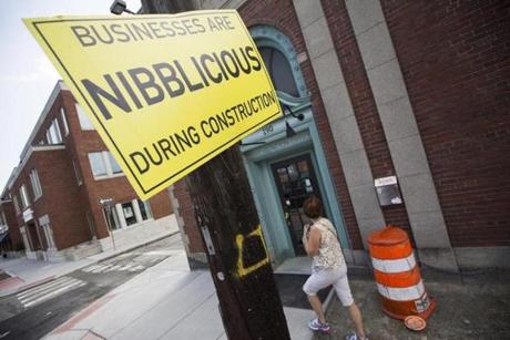 Arlington, Massachusetts - 8/25/2015 - Passersby walk under mitation construction signs hung to promote local businesses during construction along Massachusetts Avenue in Arlington, Massachusetts, August 25, 2015. (Keith Bedford/Globe Staff) 
