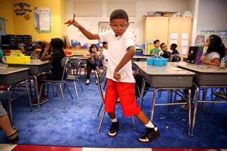 Second grader Aiden Greene, 7, practices his dance moves before a GoNoodle break during the first day of class at Salemwood School in Malden. 
