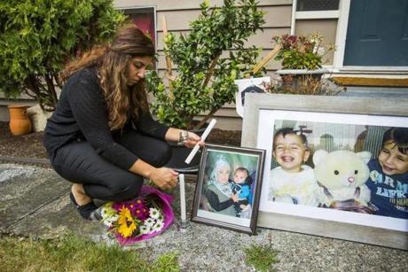 Nissy Koye, friend of Tima Kurdi, the sister of Syrian refugee Abdullah Kurdi whose sons Aylan and Galip and wife Rehan were among 12 people who drowned in Turkey trying to reach Greece, lights a candle near photographs of the boys outside Tima's home in Coquitlam, British Columbia September 3, 2015. A photograph of the tiny body of 3-year old Aylan Kurdi washed up in the Aegean resort of Bodrum swept social media on Wednesday and featured on front pages on Thursday, spawning sympathy and outrage at the perceived inaction of developed nations in helping refugees. REUTERS/
