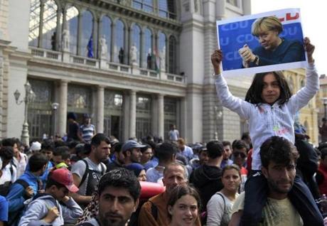 A young girl held up a picture of German Chancellor Angela Merkel as migrants set off for the border with Austria from Budapest, Hungary, on Friday. Many marchers hope to reach Germany. 
