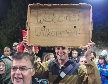 A man held a cardboard sign as refugees arrived at the Saalfeld, Germany, train station on Saturday.
