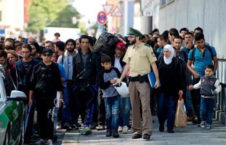 A policeman led migrants to a temporary shelter upon their arrival in Munich from Budapest on Saturday.
