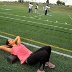 John D. O'Bryant High School junior Lila Hernandez foam rolled her back as she and the track team worked out during the opening of the West Roxbury Education Complex Raiders Field on Saturday.