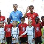 Bayern Munich soccer team members Phillipp Lahm, Manuel Neuer, and Thomas Mueller with migrant children.