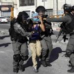 sraeli police officers detain a Palestinian youth during clashes in the Shuafat refugee camp in Jerusalem Friday.