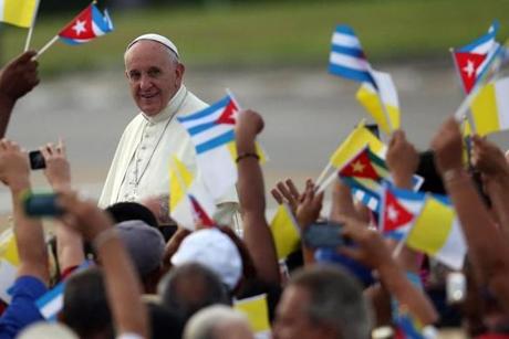 HAVANA, CUBA - SEPTEMBER 20: People wave Cuban and Papal flags as Pope Francis passes by as he arrives to perform Mass on September 20, 2015 in Revolution Square in Havana, Cuba. Pope Francis is on the first full day of his three day visit to Cuba where he will meet President Raul Castro and hold Mass in Revolution Square before travelling to Holguin, Santiago de Cuba and El Cobre then onwards to the United States. (Photo by Carl Court/Getty Images)
