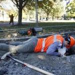 Archeologist Sam Rousseau leaned down to record the color and texture of the soil inside a hole he dug as part of an archeological dig that began Monday on Boston Common.