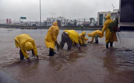 Municipal workers collected branches from a flooded street in Manzanillo, Colima state, Mexico on Friday.
