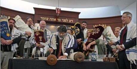 At Temple Sinai in Sharon, a completion ceremony was held recently to mark the end of an 18-month project to restore a beloved Torah scroll that survived the Holocaust in Bohemia and Moravia. Torah scribe Rabbi Kevin Hale prepares to enter the second of three final letters to the scroll. Behind him are representatives of other area congregations in possession of Czech Torah scrolls. (George Rizer for the Globe) 
