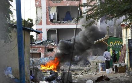 Somali men watched as fires burned amidst the destruction outside the Sahafi Hotel in Mogadishu. 
