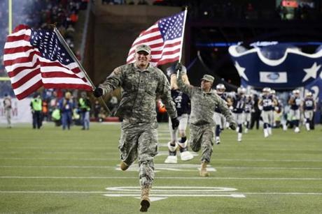 Military service men lead the New England Patriots onto the field before an NFL football game against the Denver Broncos Sunday, Nov. 24, 2013, in Foxborough, Mass., to honor veterans and active duty military members as part of the NFL's Salute to Service. (AP Photo/Elise Amendola)

