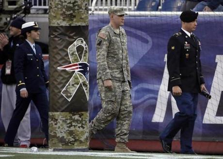 Members of the U.S. military walk past a goal post decorated to acknowledge Salute to Service activities before an NFL football game between the New England Patriots and the Detroit Lions Sunday, Nov. 23, 2014, in Foxborough, Mass. (AP Photo/Stephan Savoia)
