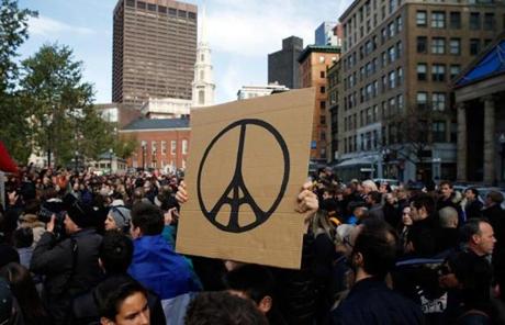 A man held a sign that combined the peace symbol and the Eiffel Tower at Boston Common.
